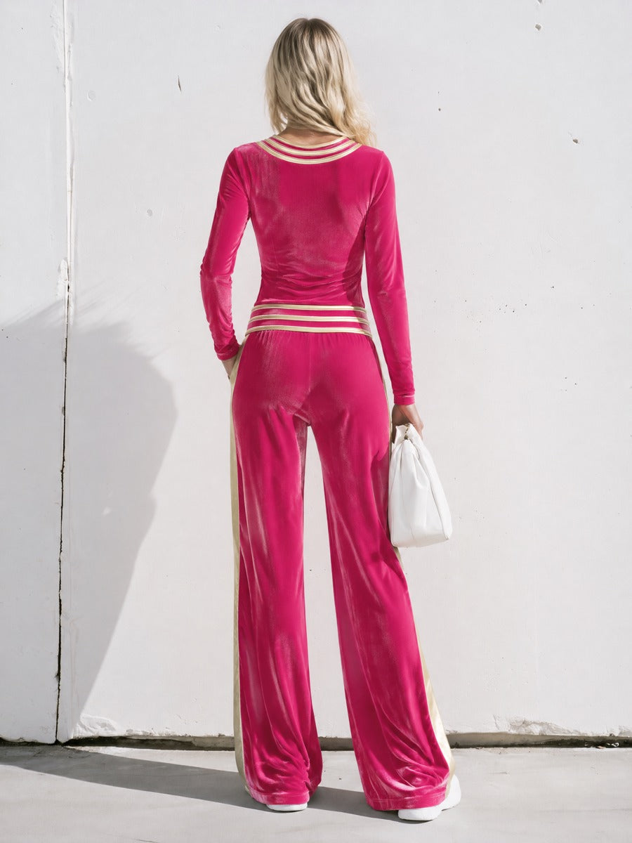 Bright pink velvet women's two-piece set by Oyrosy Clothing, featuring gold striped T-shirt and wide-leg pants.