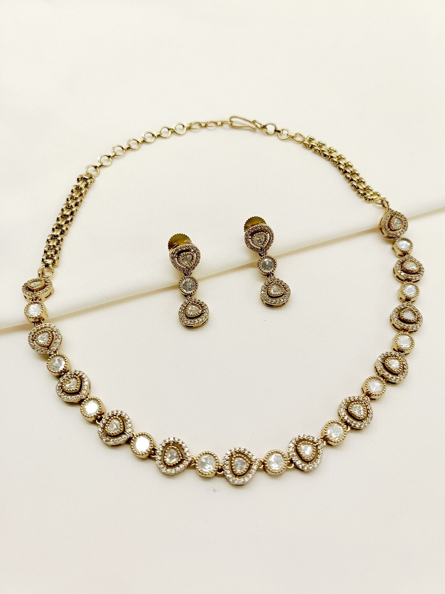 Close up of Amla White Polki Necklace Set on a black background, showcasing delicate antique gold plated brass metal and exquisite American diamond setting