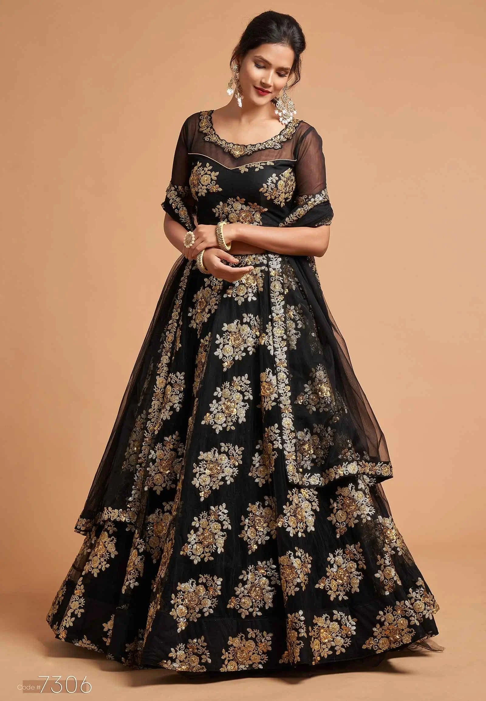 Woman wearing black floral embroidered lehenga with sheer sleeves and gold jewelry