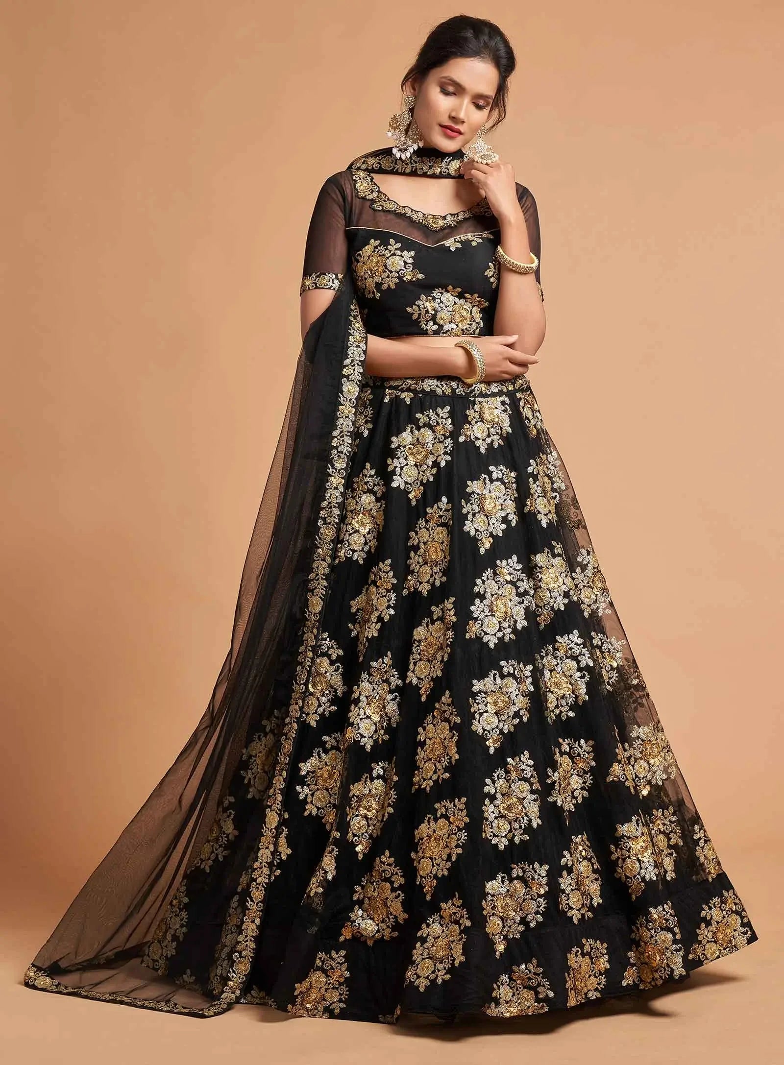 Woman wearing black floral embroidered lehenga with sheer dupatta and gold jewelry