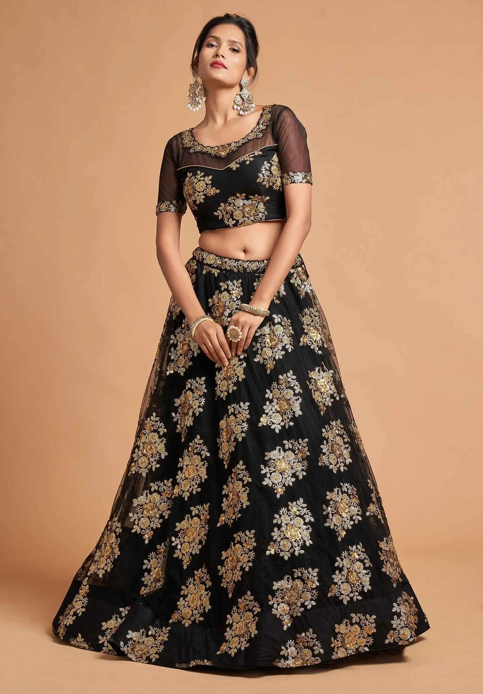 Woman wearing black floral embroidered lehenga choli with sheer sleeves and gold jewelry