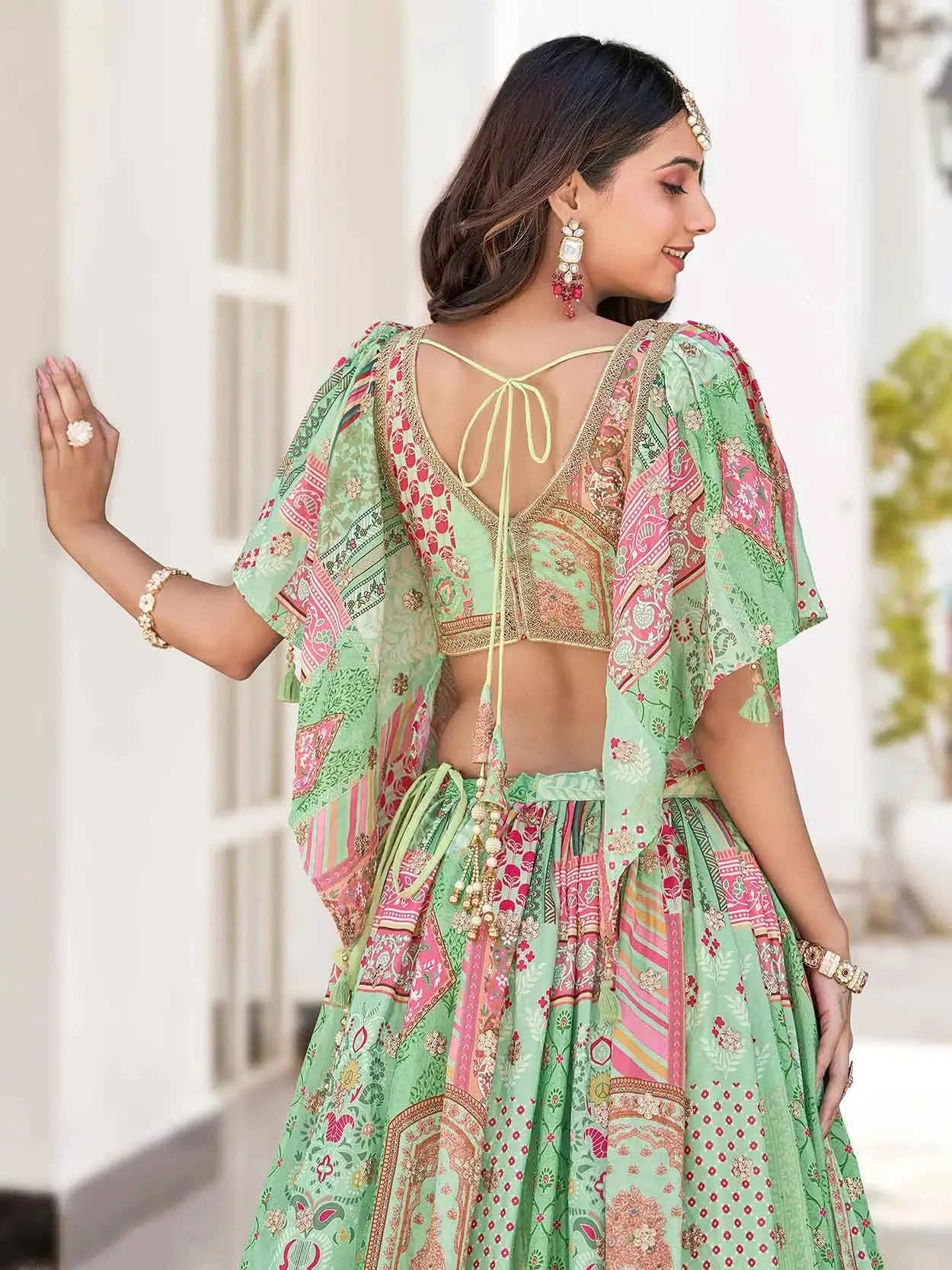 Woman in green floral printed lehenga choli with tie-back blouse and statement jewelry