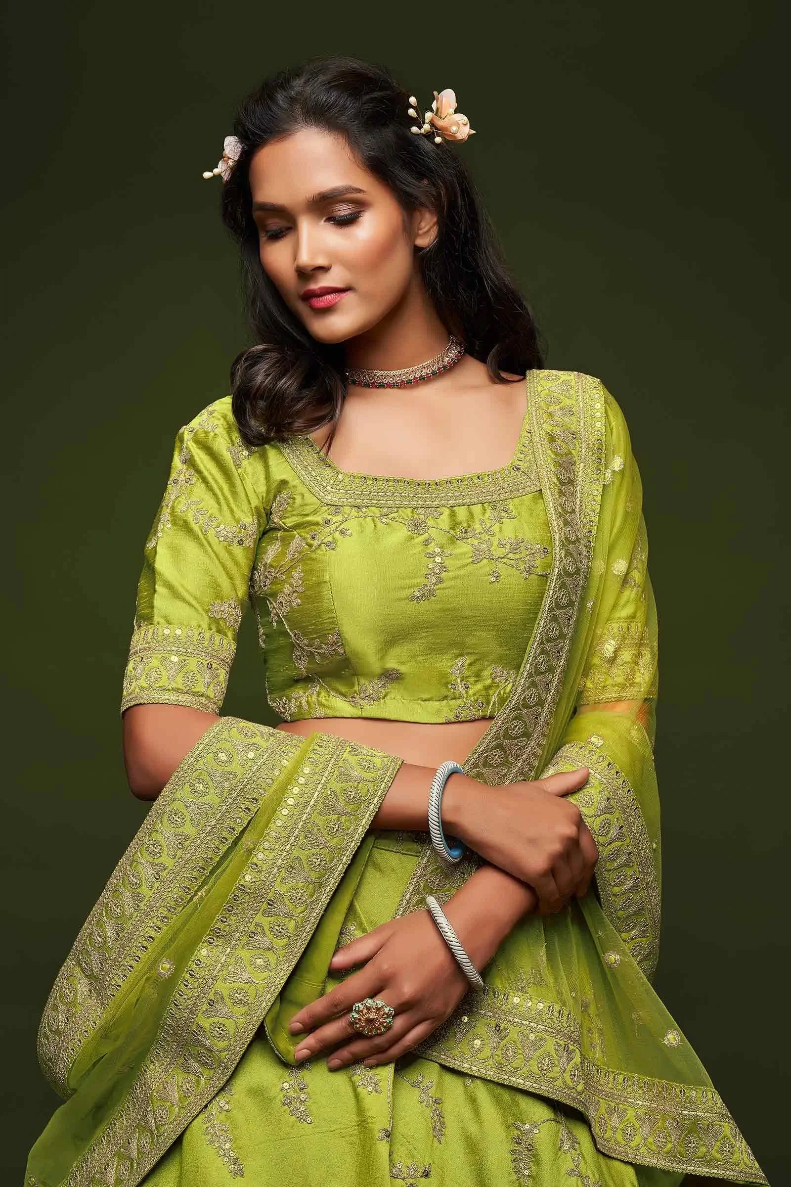 Woman in embroidered green lehenga choli with jewelry and floral hair accessories