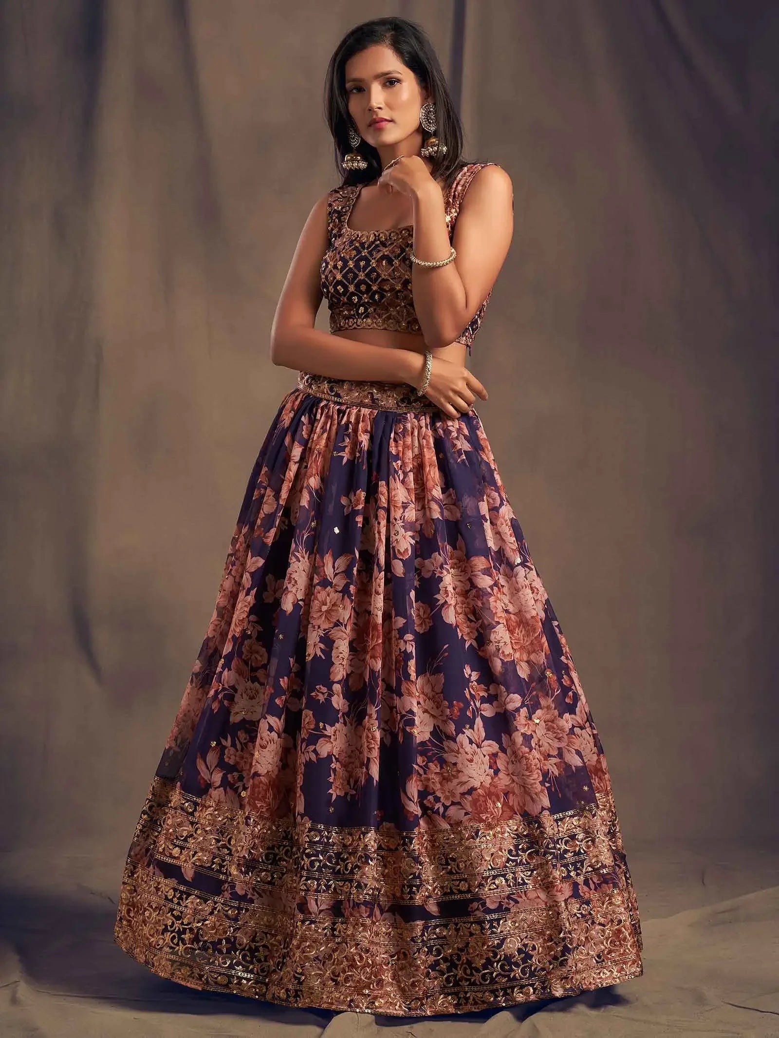 Woman in navy blue and gold floral lehenga choli, traditional jewelry, studio background