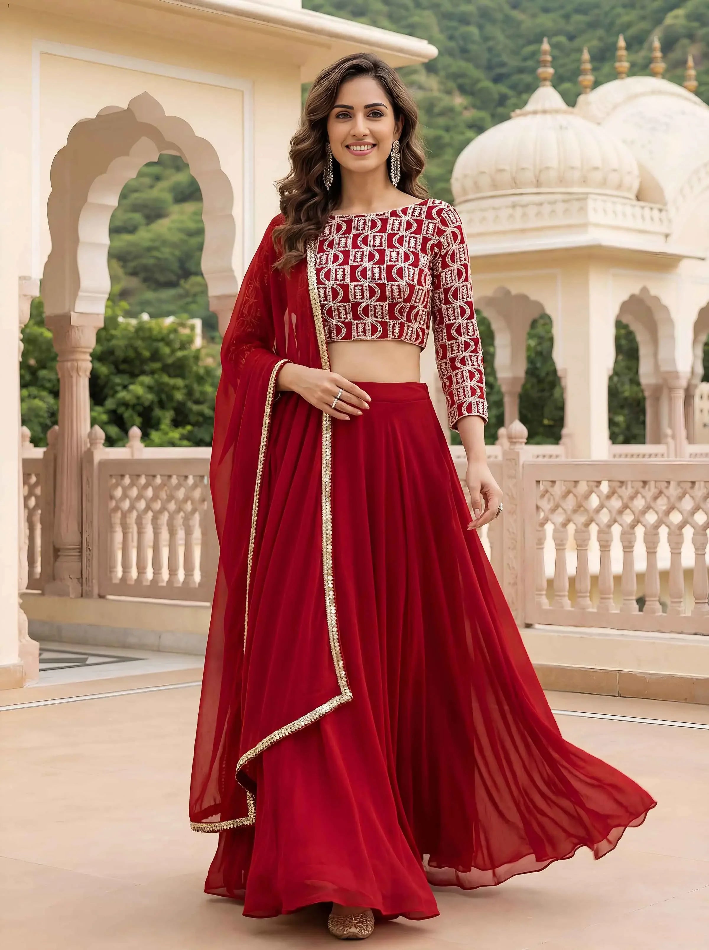 Woman in elegant red lehenga choli with gold trim, standing in traditional outdoor setting
