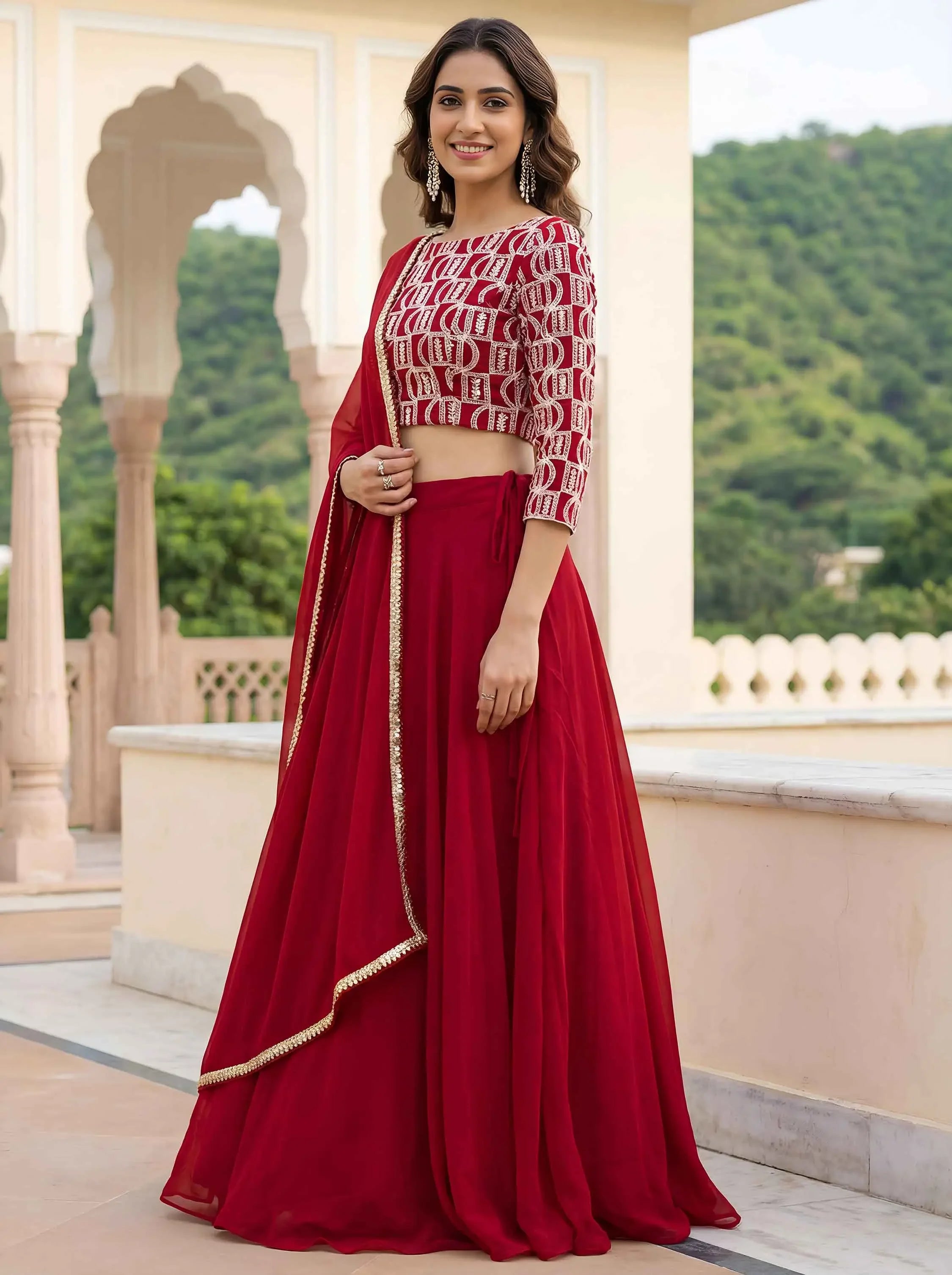 Woman wearing a red lehenga with geometric blouse and dupatta in a traditional outdoor setting