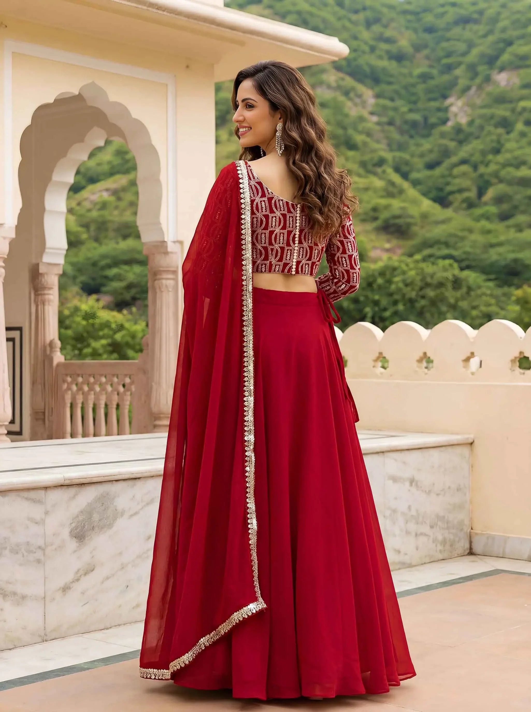 Woman in a red lehenga with embroidered blouse and dupatta, standing outdoors