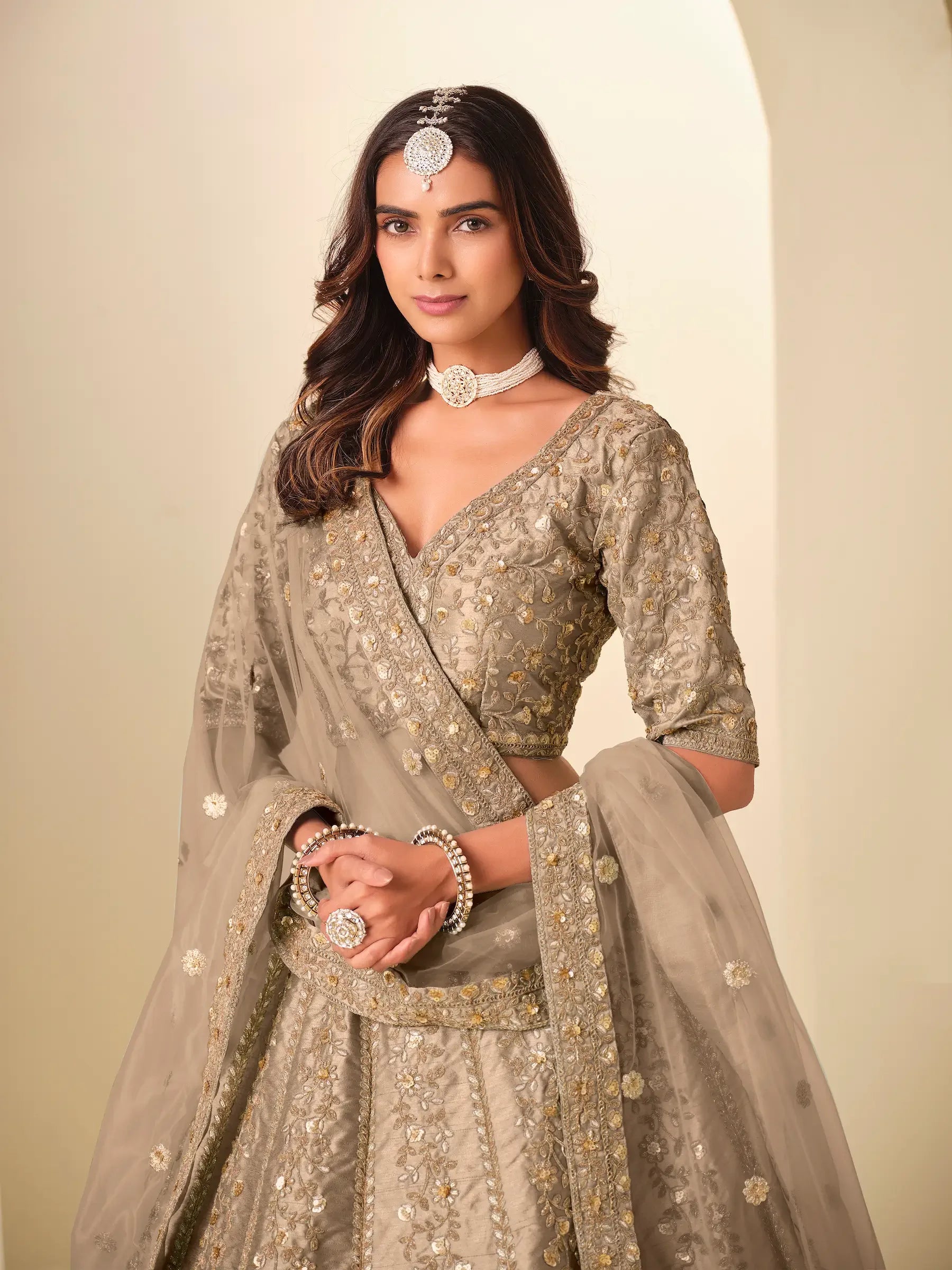 Woman wearing gold embroidered lehenga with matching dupatta and traditional jewelry