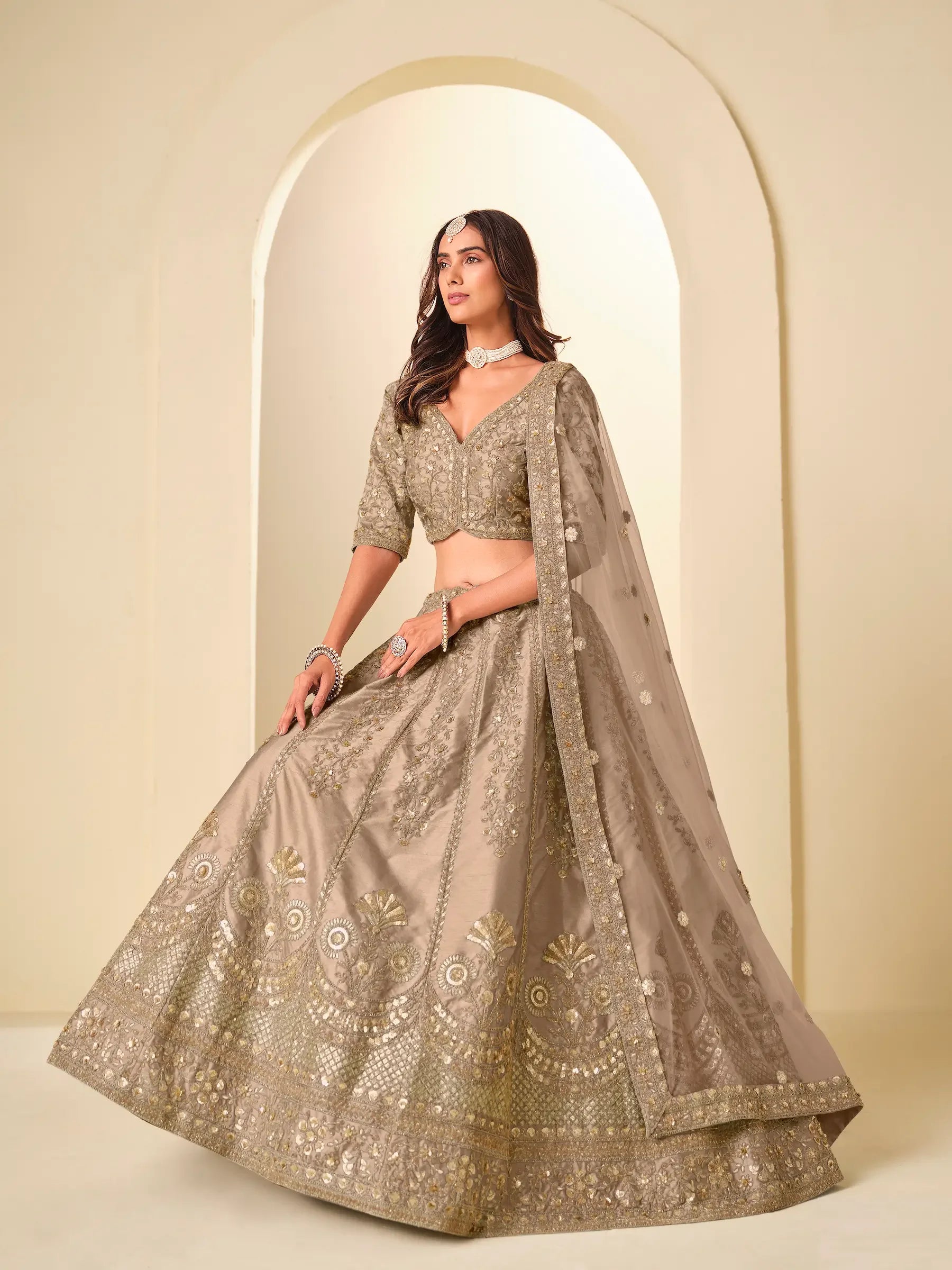 Woman wearing gold embroidered lehenga choli with dupatta, traditional Indian attire