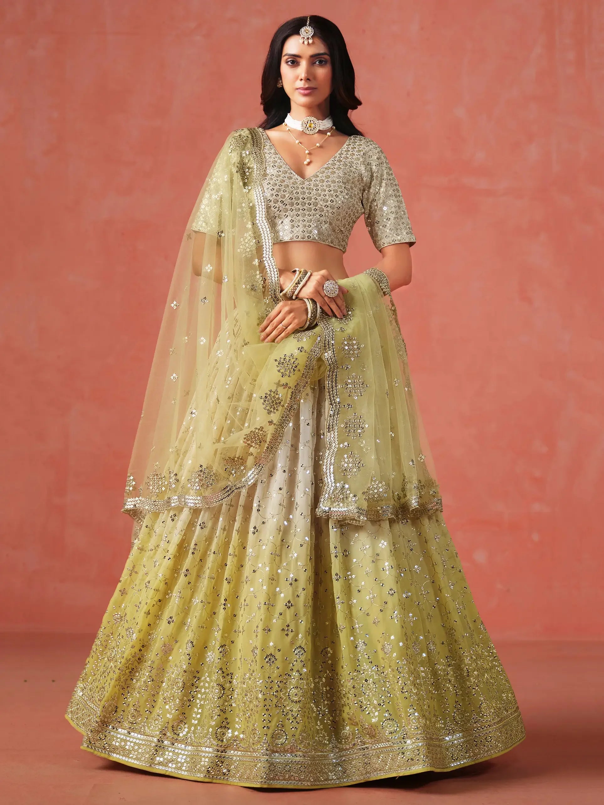 Woman wearing an embellished yellow lehenga choli with dupatta, traditional jewelry