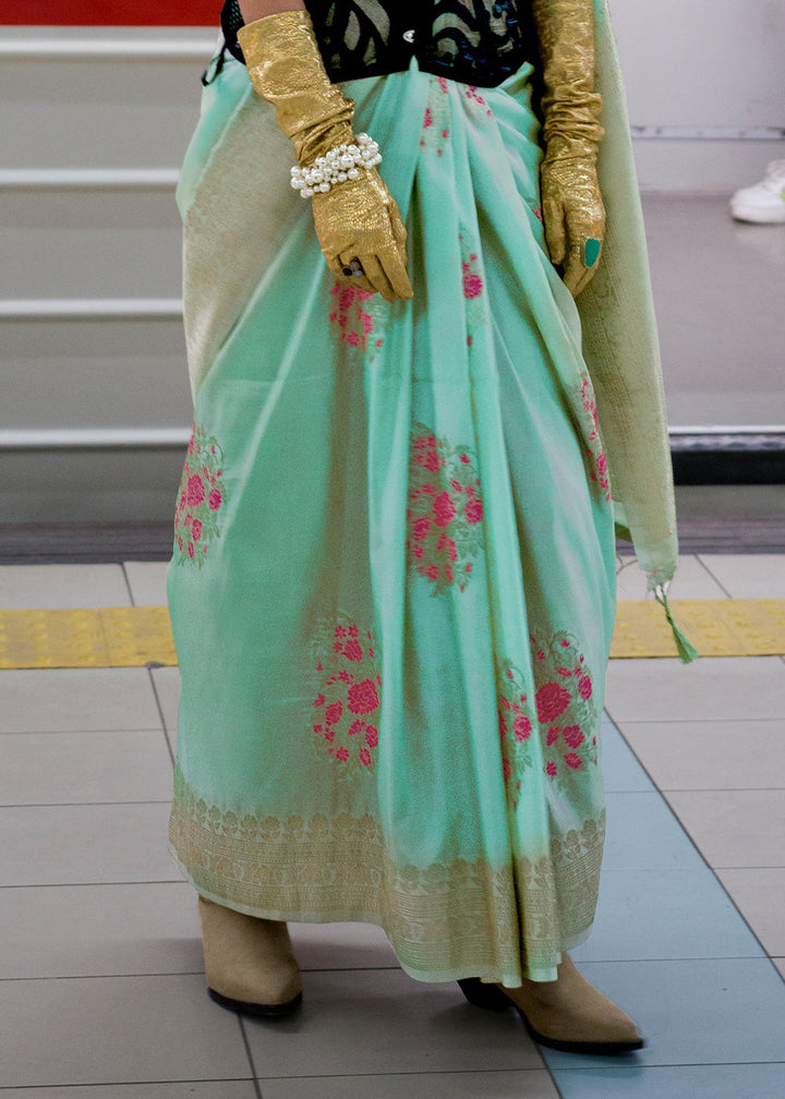 A close-up image of a mint green handloom woven Banarasi silk saree with intricate floral patterns