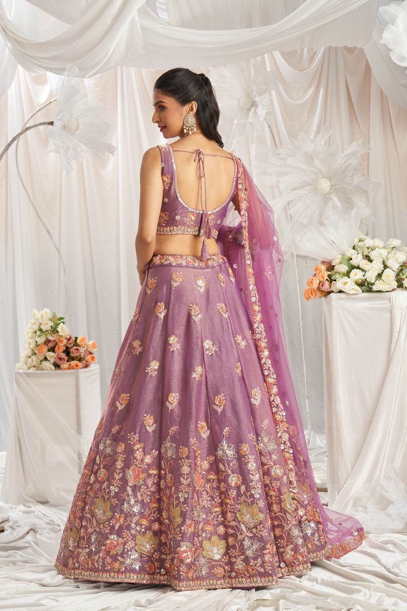 Back view of Lavender Organza Sequins embroidery Semi-Stitched Lehenga choli & Dupatta, showcasing the flowy and ethereal organza fabric and the intricate sequin detailing on the back of the choli The semi-stitched design allows for a customizable fit, while the delicate embroidery adds a touch of glamour and sophistication to the overall look The matching dupatta completes the ensemble with its beautiful sequin embroidery, making it a stunning choice for special occasions or traditional events