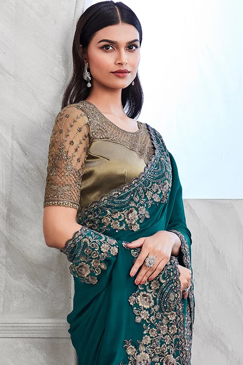  Elegant teal blue silk saree with floral embellishments, paired with a fancy walnut blouse on display