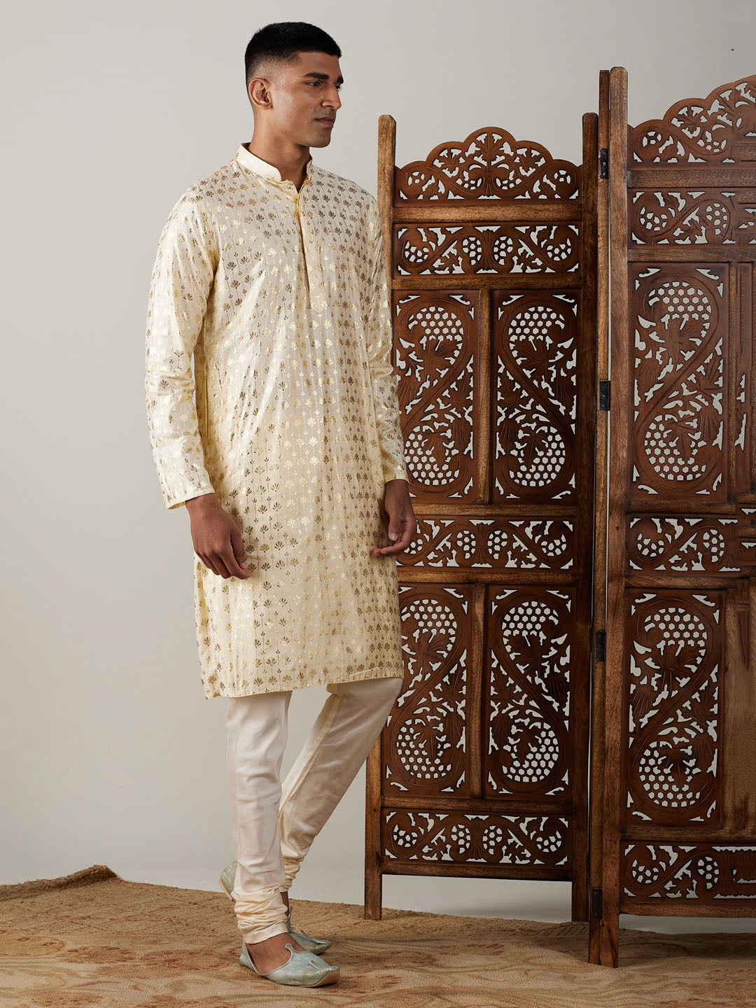 A traditional Indian men's outfit, the VASTRAMAY Men's Gold Foil Printed Kurta With Cream Pyjama Set features intricate gold foil detailing on a cream-colored kurta paired with matching pyjamas