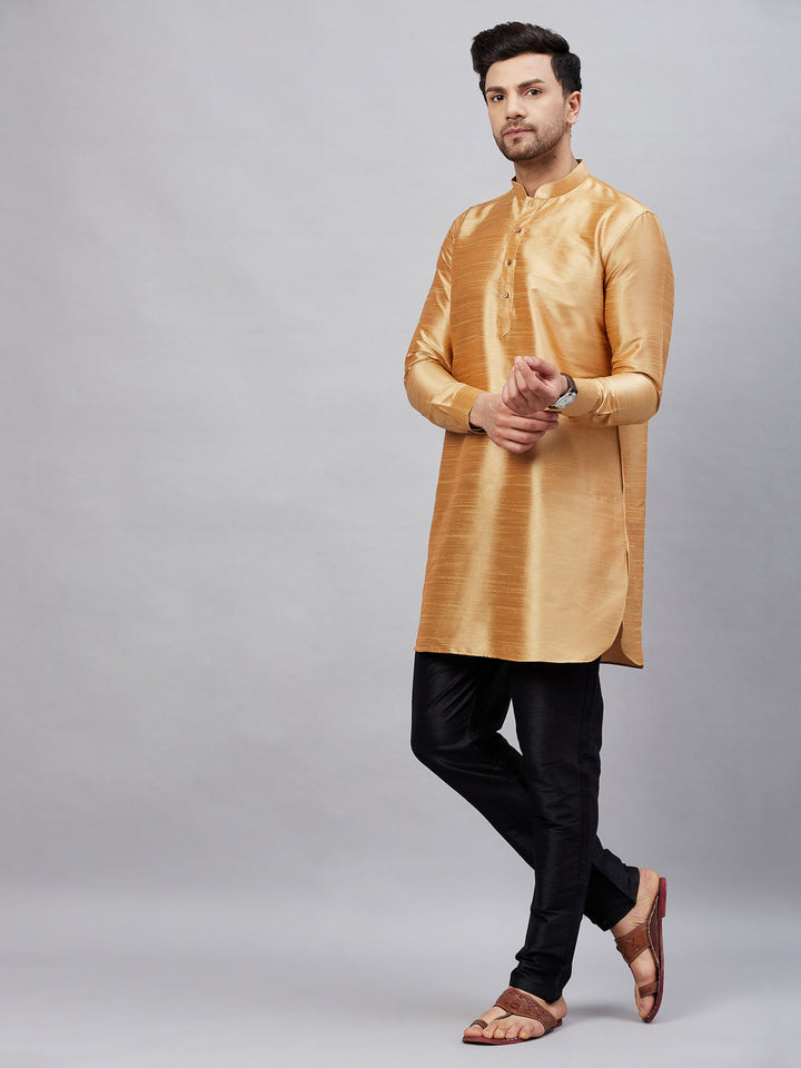 A man wearing VM By VASTRAMAY Men's Rose Gold Silk Blend Curved Kurta Pant Set, perfect for traditional occasions