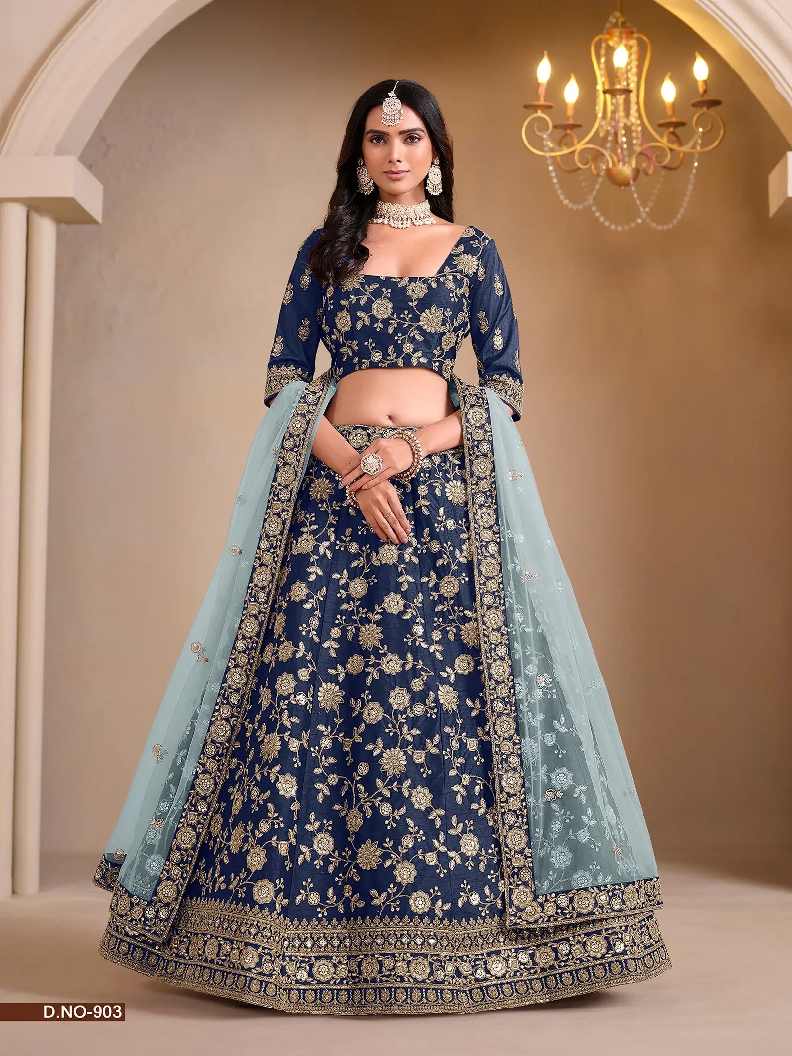 Woman wearing navy blue embroidered lehenga choli with gold floral patterns and light blue dupatta