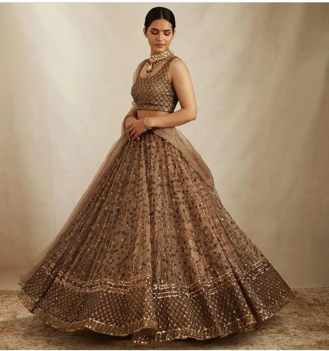 Woman in an ornate gold embroidered lehenga with sleeveless blouse and traditional jewelry