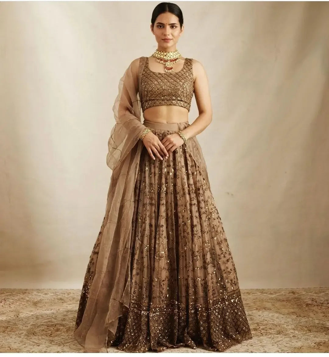 Woman wearing a gold sequined lehenga set with matching blouse and dupatta, traditional jewelry