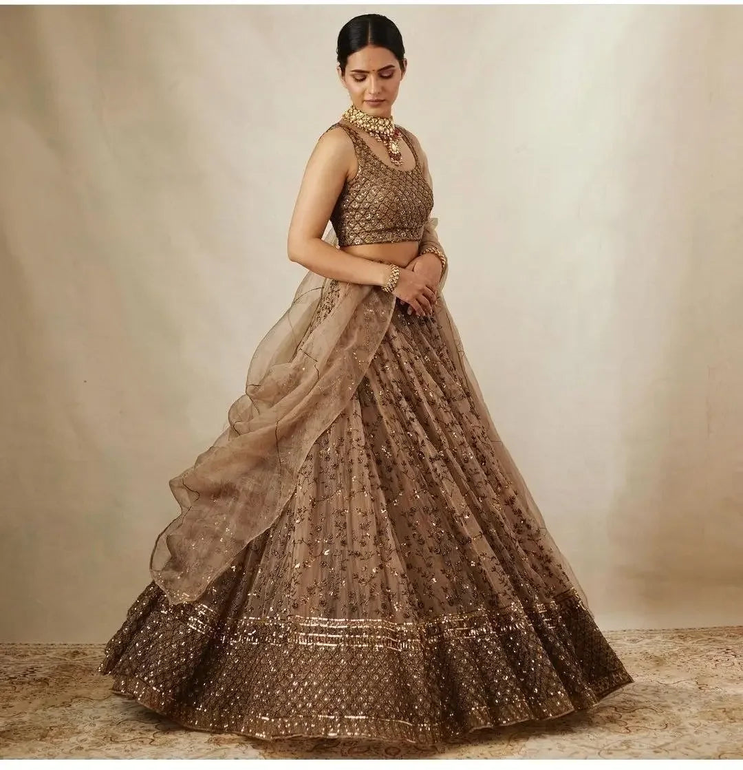 Woman in gold embroidered lehenga choli with dupatta, traditional Indian attire