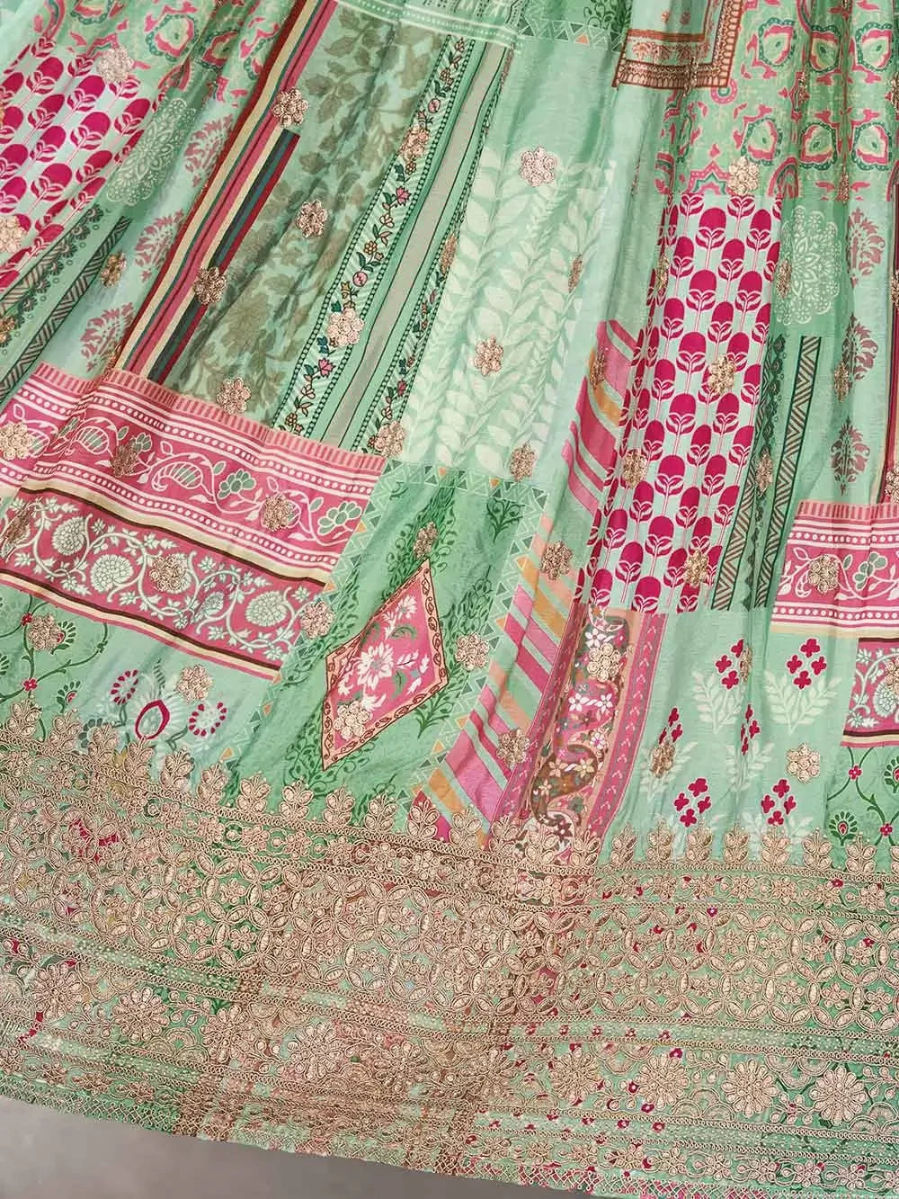 Green and pink ethnic fabric with intricate gold floral embroidery and geometric patterns