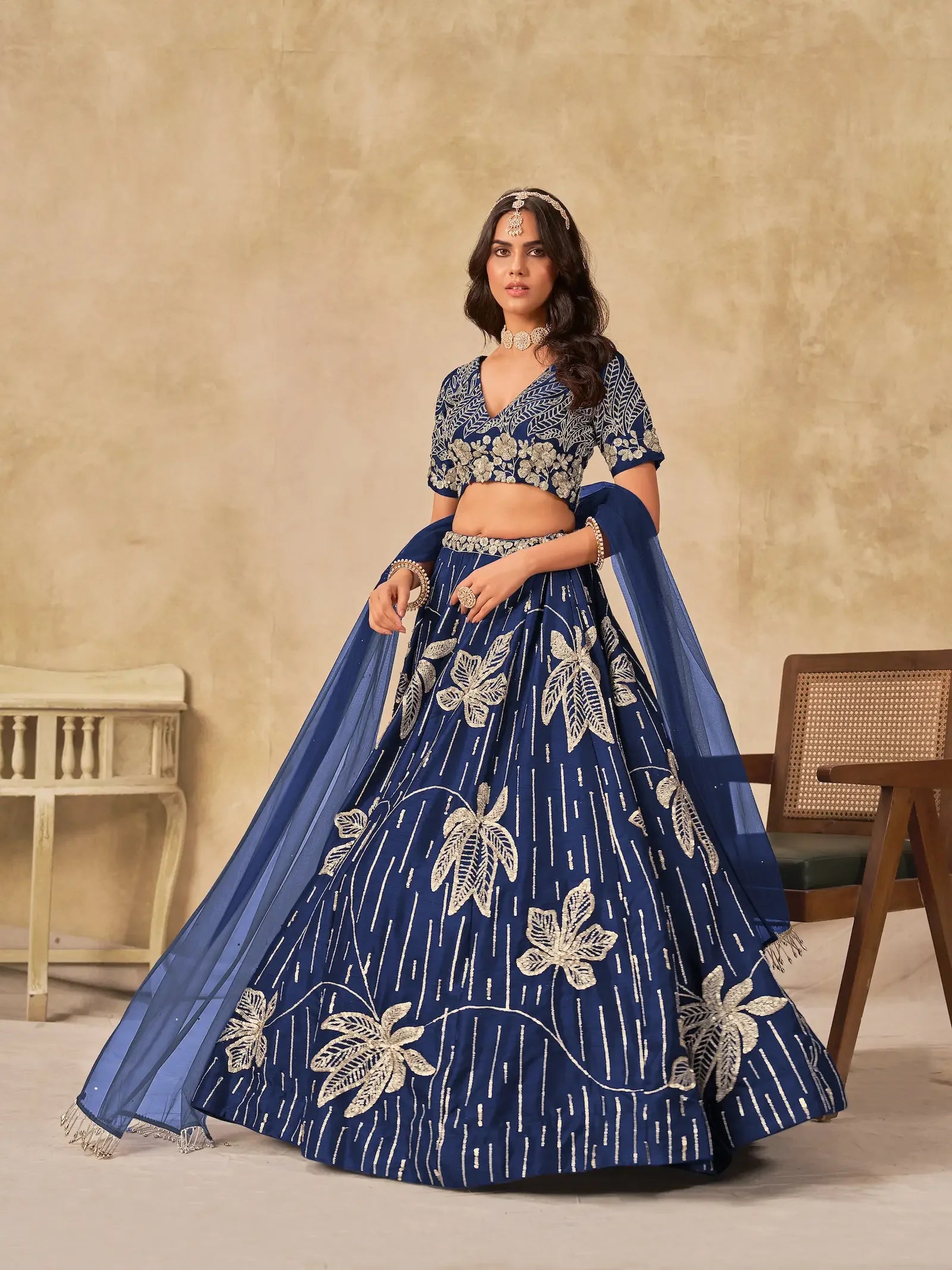 Woman wearing blue embroidered lehenga choli set with gold floral design and dupatta