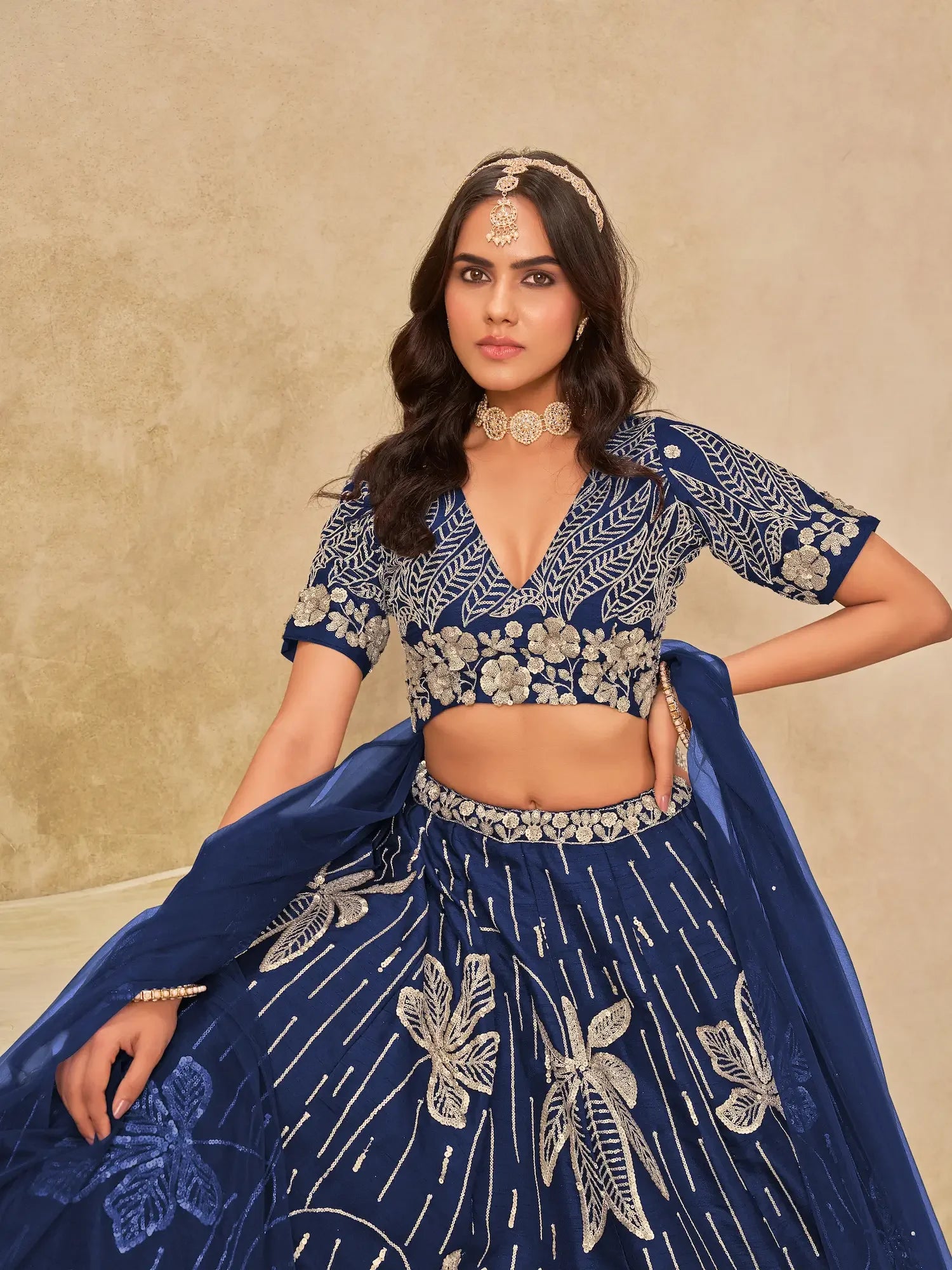 Woman in royal blue embroidered lehenga choli with silver floral designs and matching jewelry