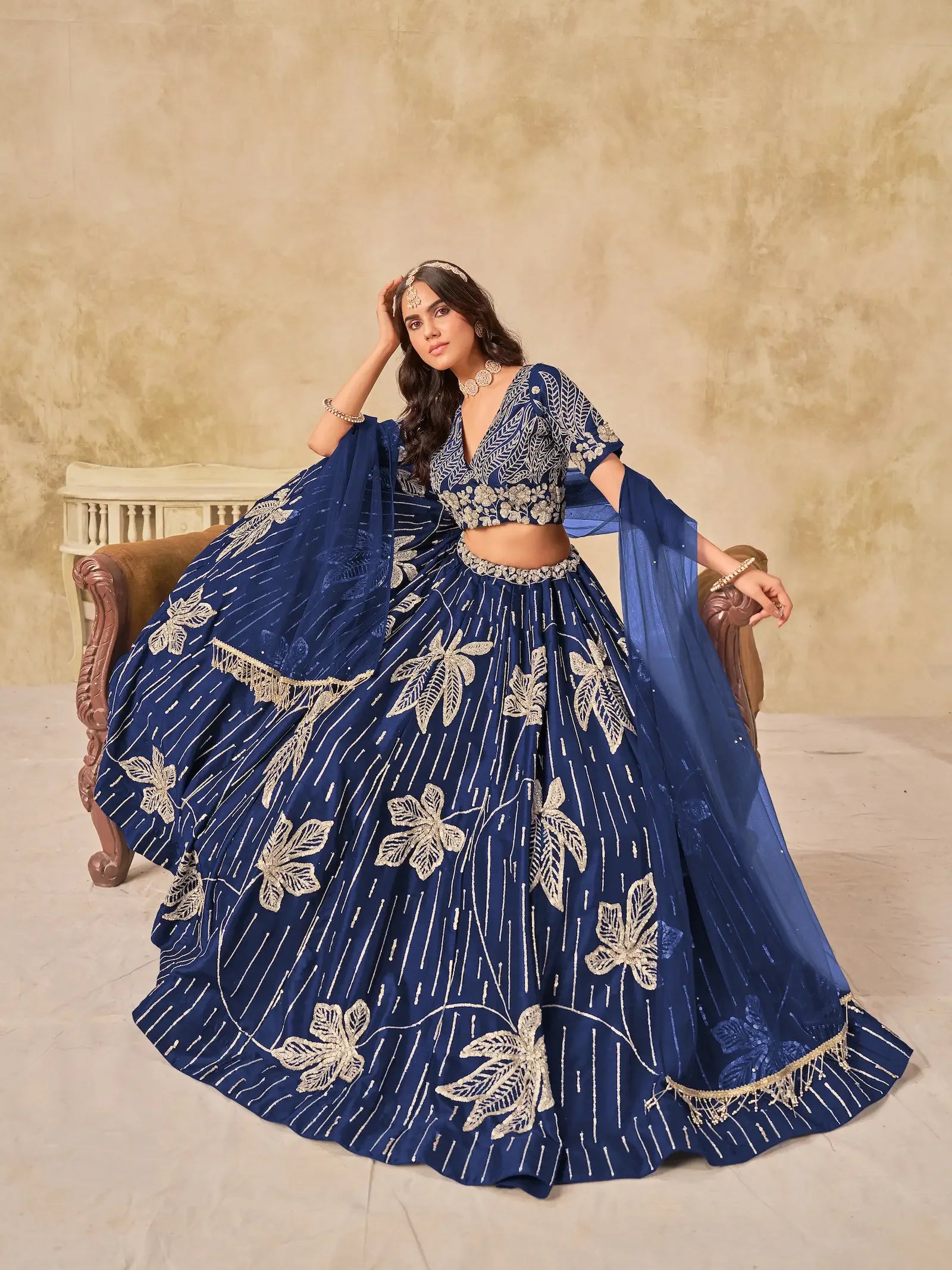 Woman in royal blue embroidered lehenga choli with floral patterns and matching dupatta