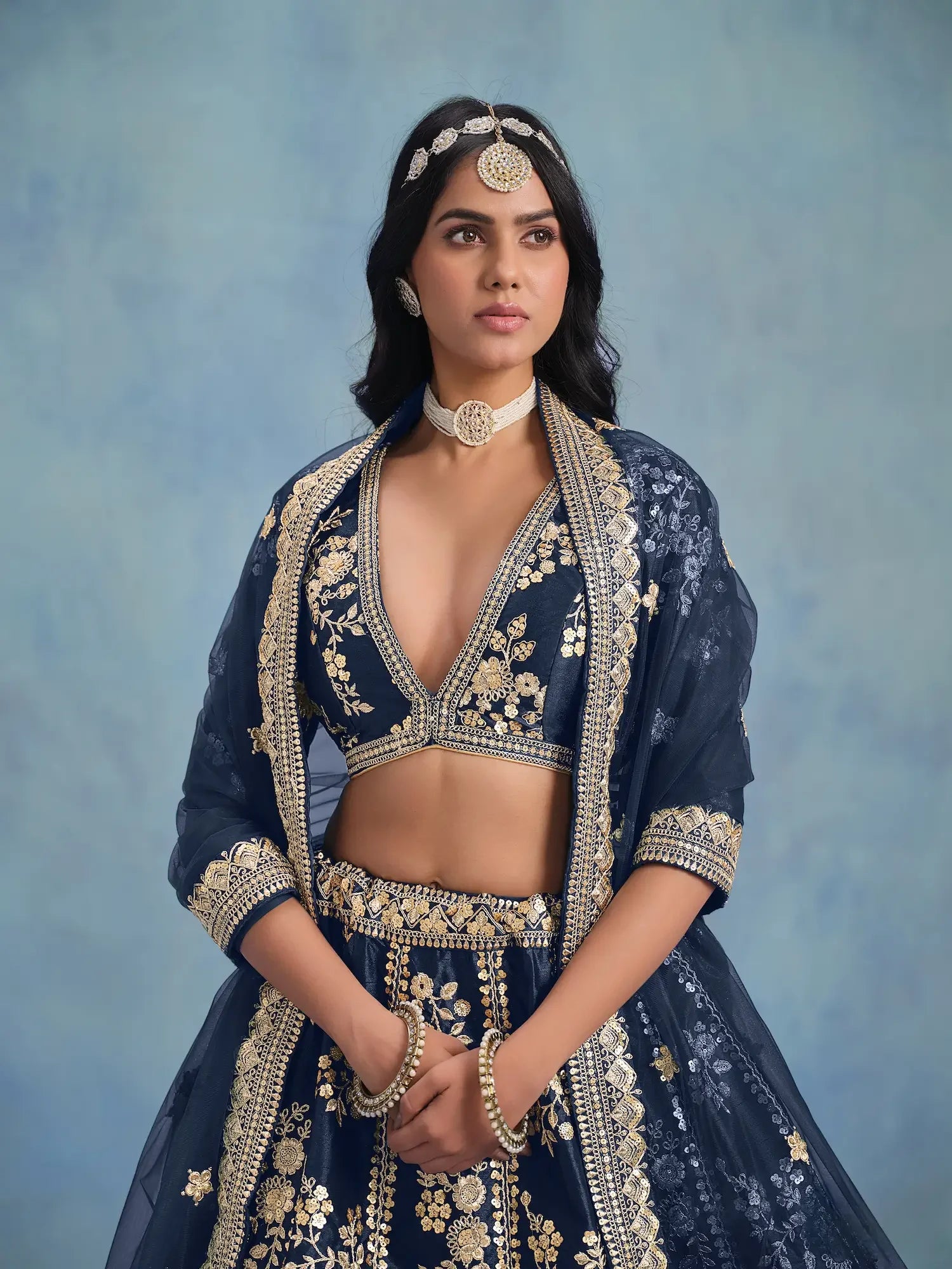 Woman in navy blue and gold embroidered lehenga with traditional Indian jewelry