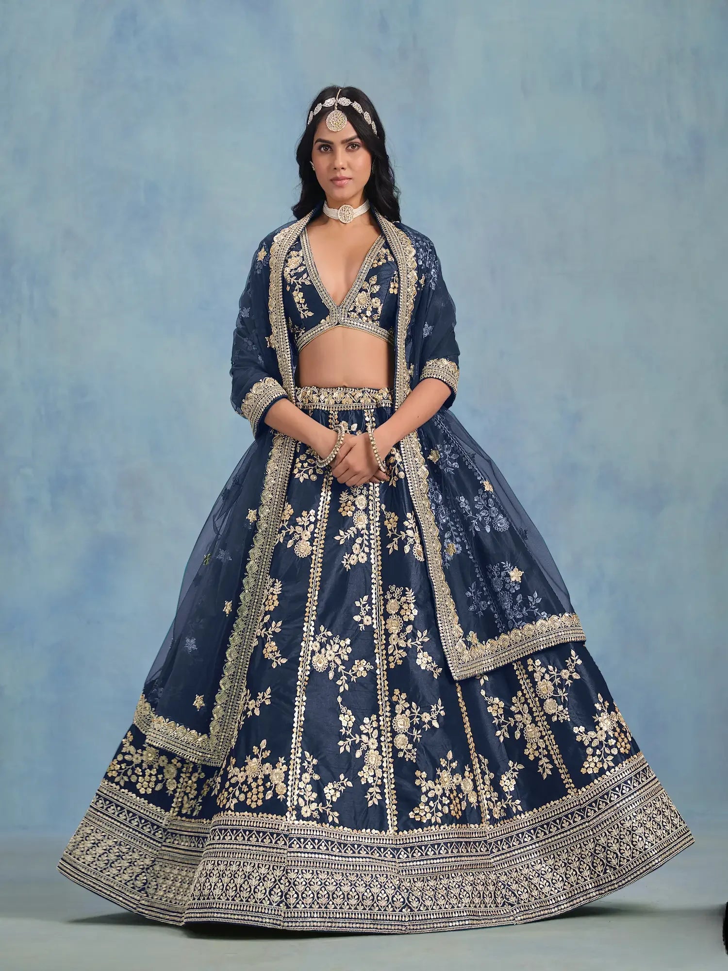 Woman in navy blue and gold embroidered lehenga with choli and dupatta, traditional attire