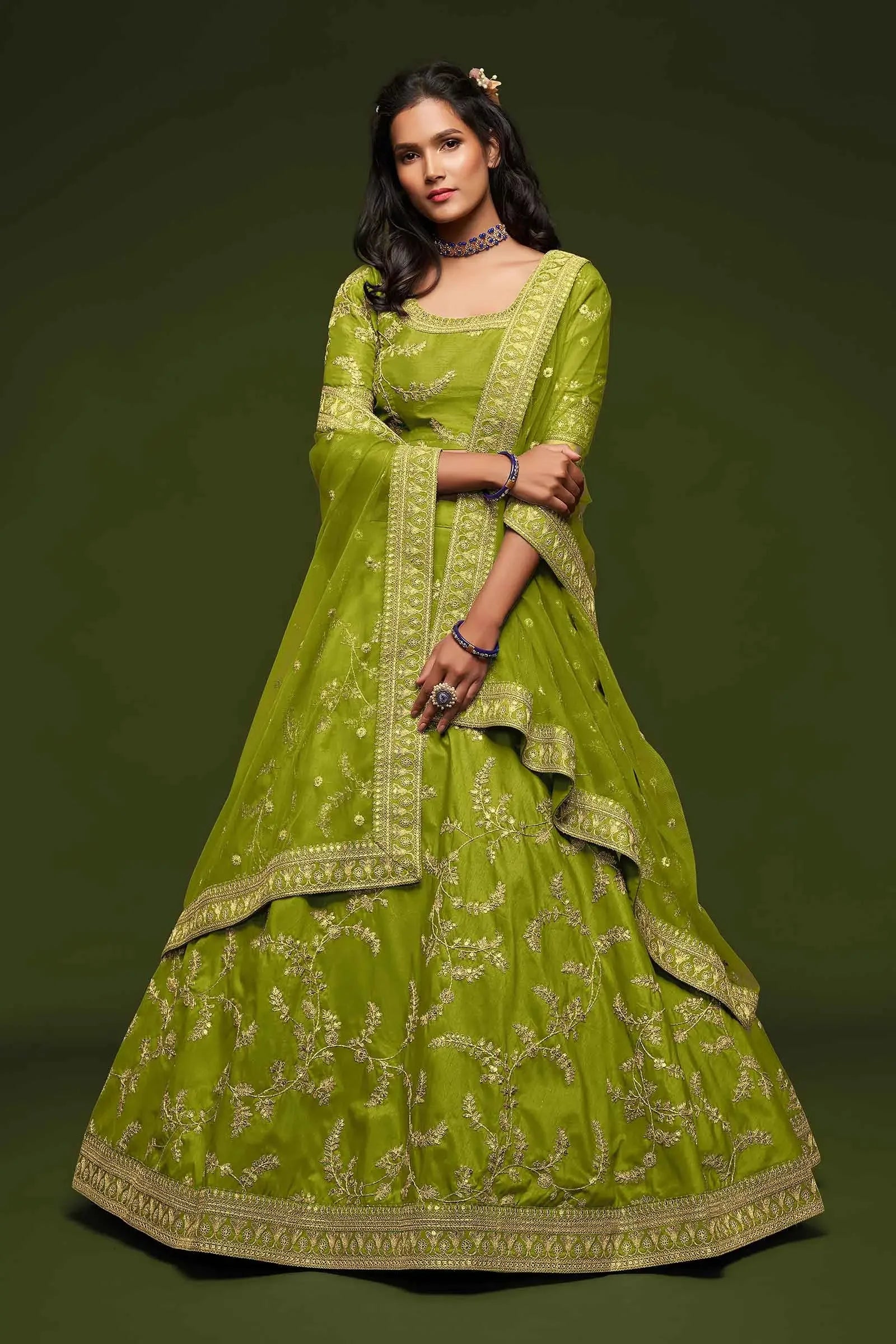 Woman wearing green embroidered lehenga with matching dupatta on solid green background