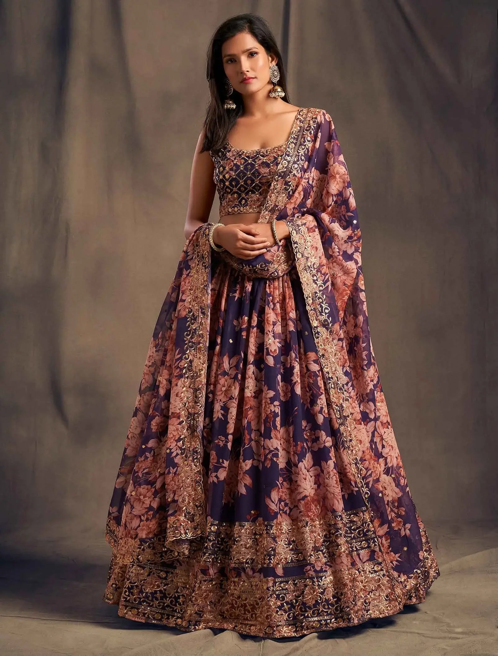 Woman wearing navy blue and pink floral lehenga choli with intricate gold embroidery