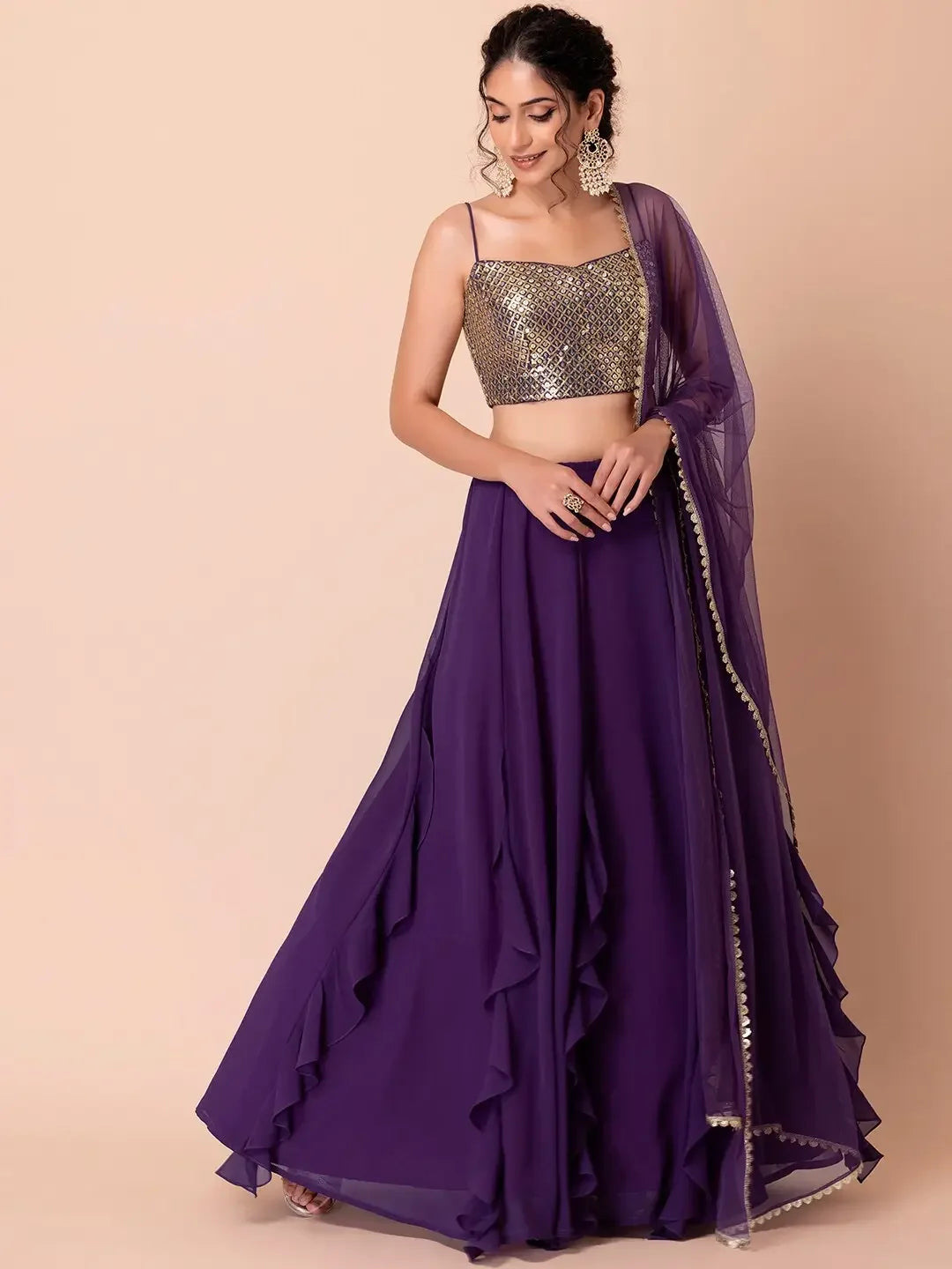 Woman wearing a purple ruffle lehenga skirt with sequined gold crop top and dupatta