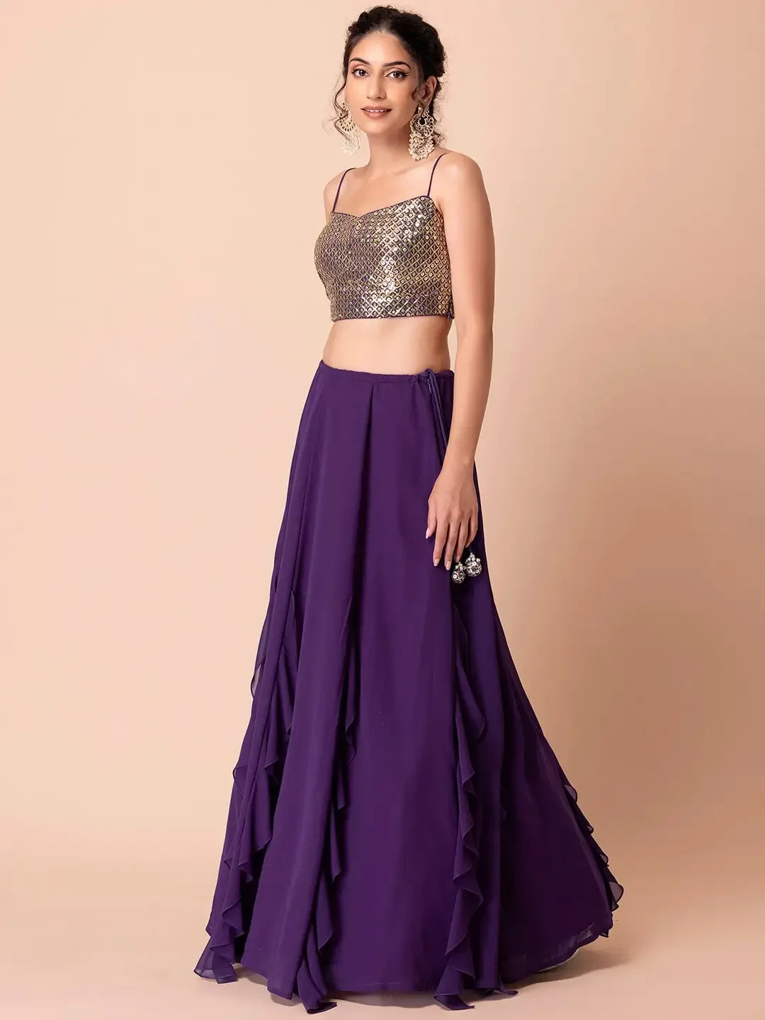 Woman wearing a gold sequin crop top and purple ruffle lehenga skirt