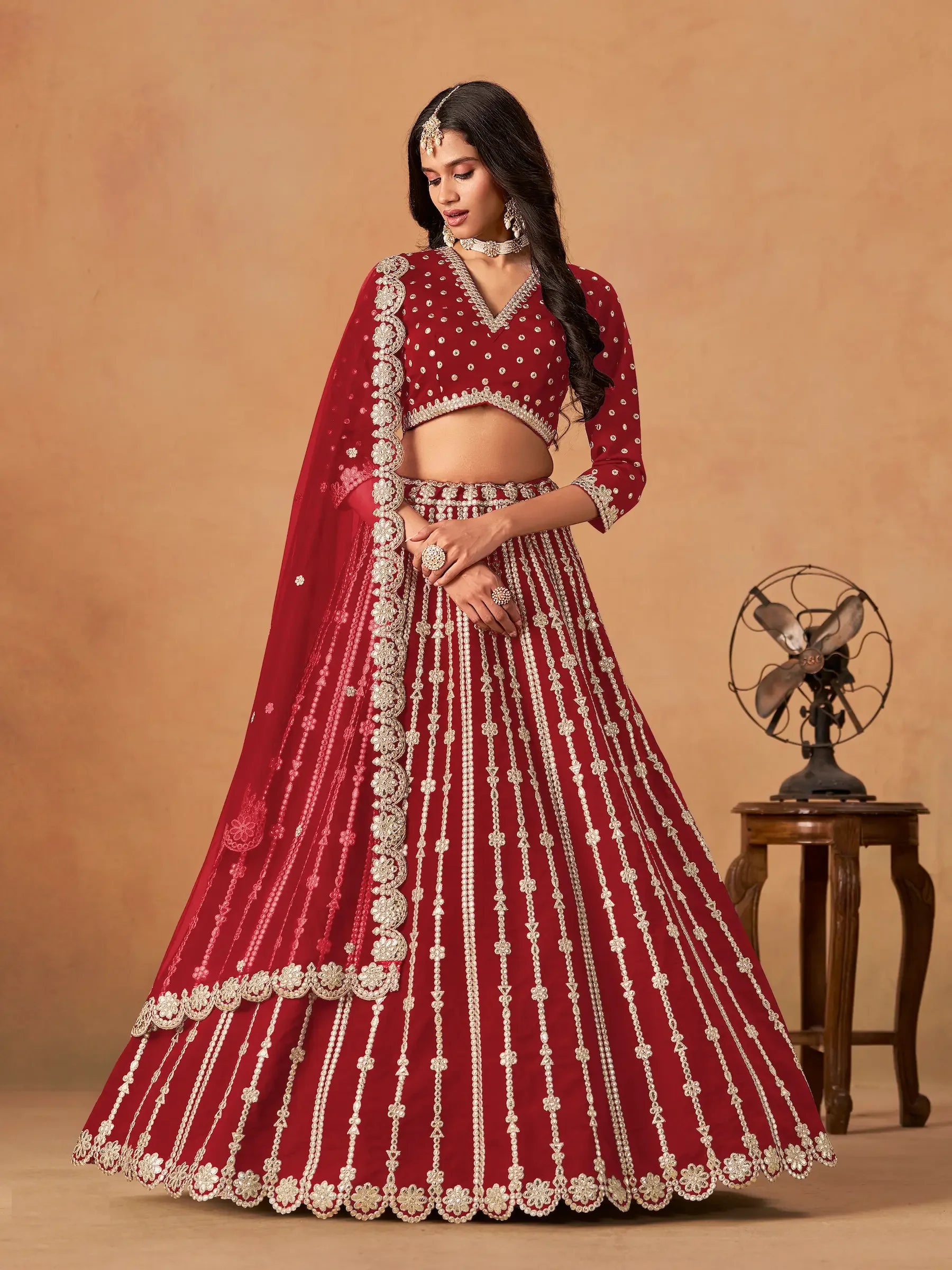 Woman wearing maroon embroidered lehenga set with dupatta, traditional jewelry
