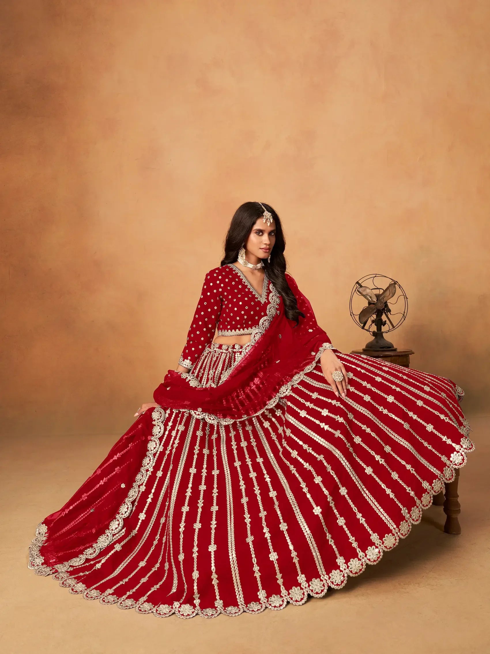 Woman in red bridal lehenga with silver embroidery, traditional jewelry, indoor setting