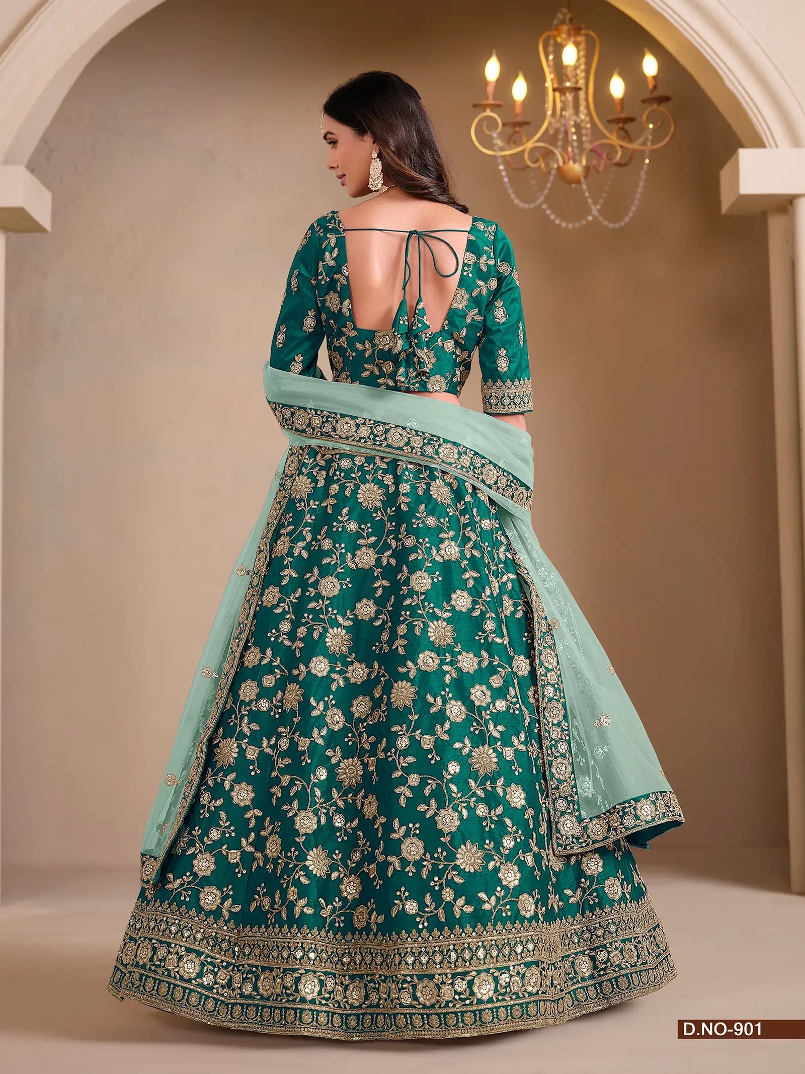 Woman in emerald green embroidered lehenga with floral patterns and dupatta, back view