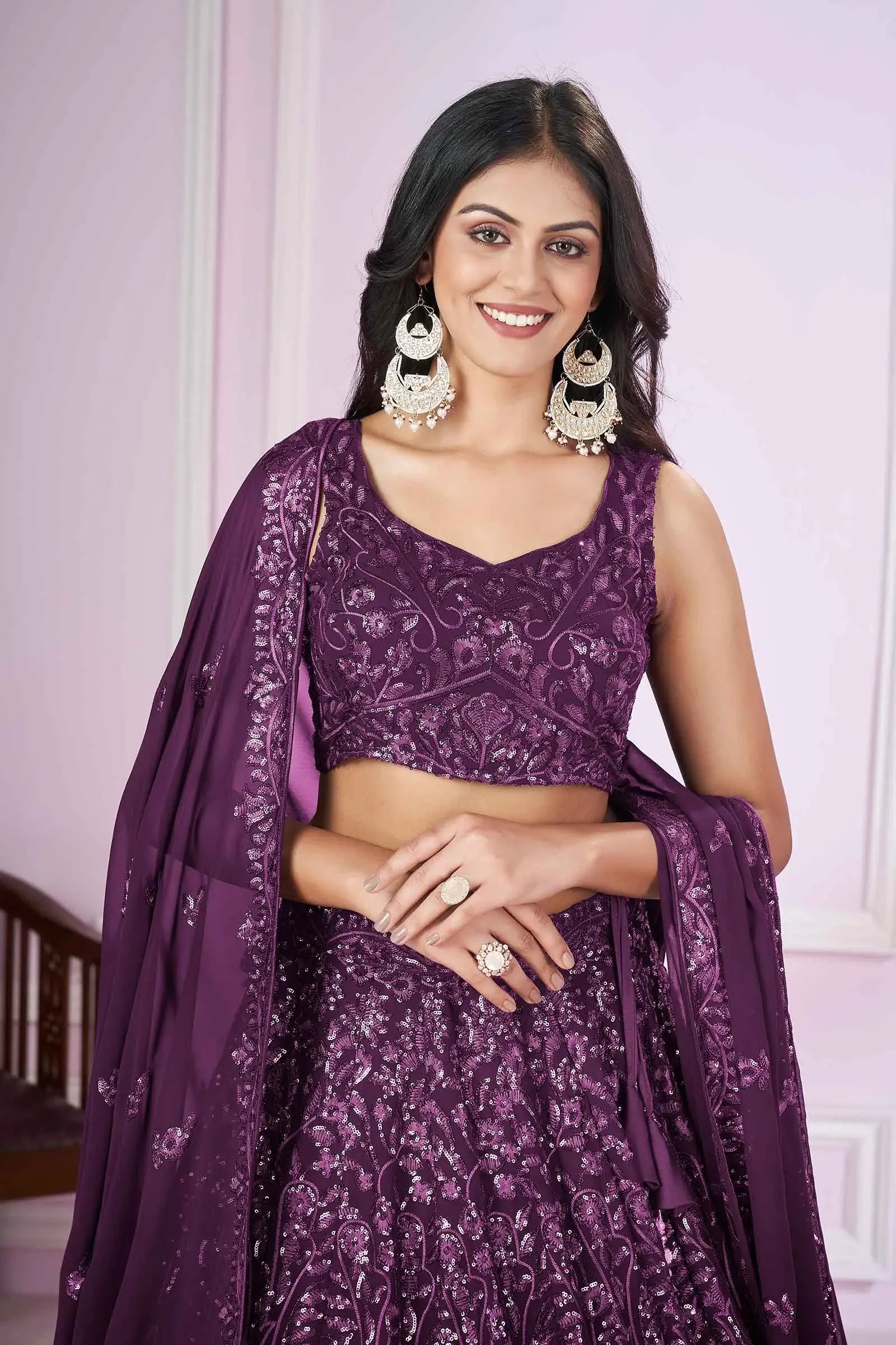 Woman in purple embroidered lehenga with dupatta and statement earrings