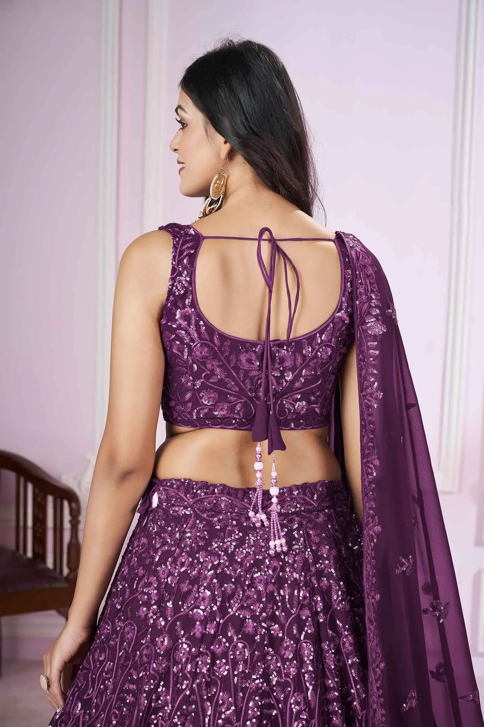 Woman in purple embroidered lehenga choli with dupatta, back view, festive wear
